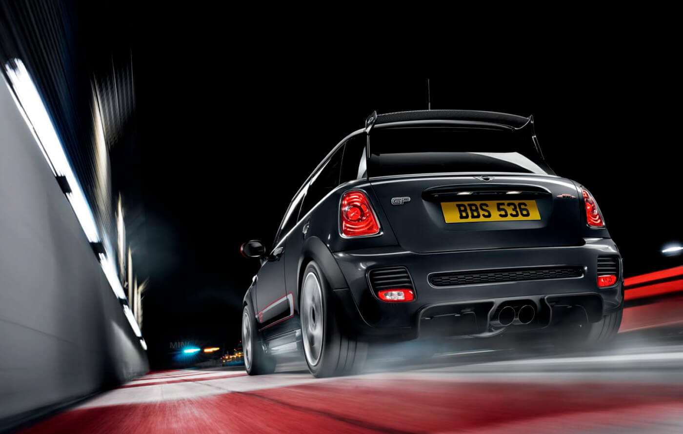 Full screen image of a dark grey Mini John Cooper Works GP Edition, driving along a race track at night
