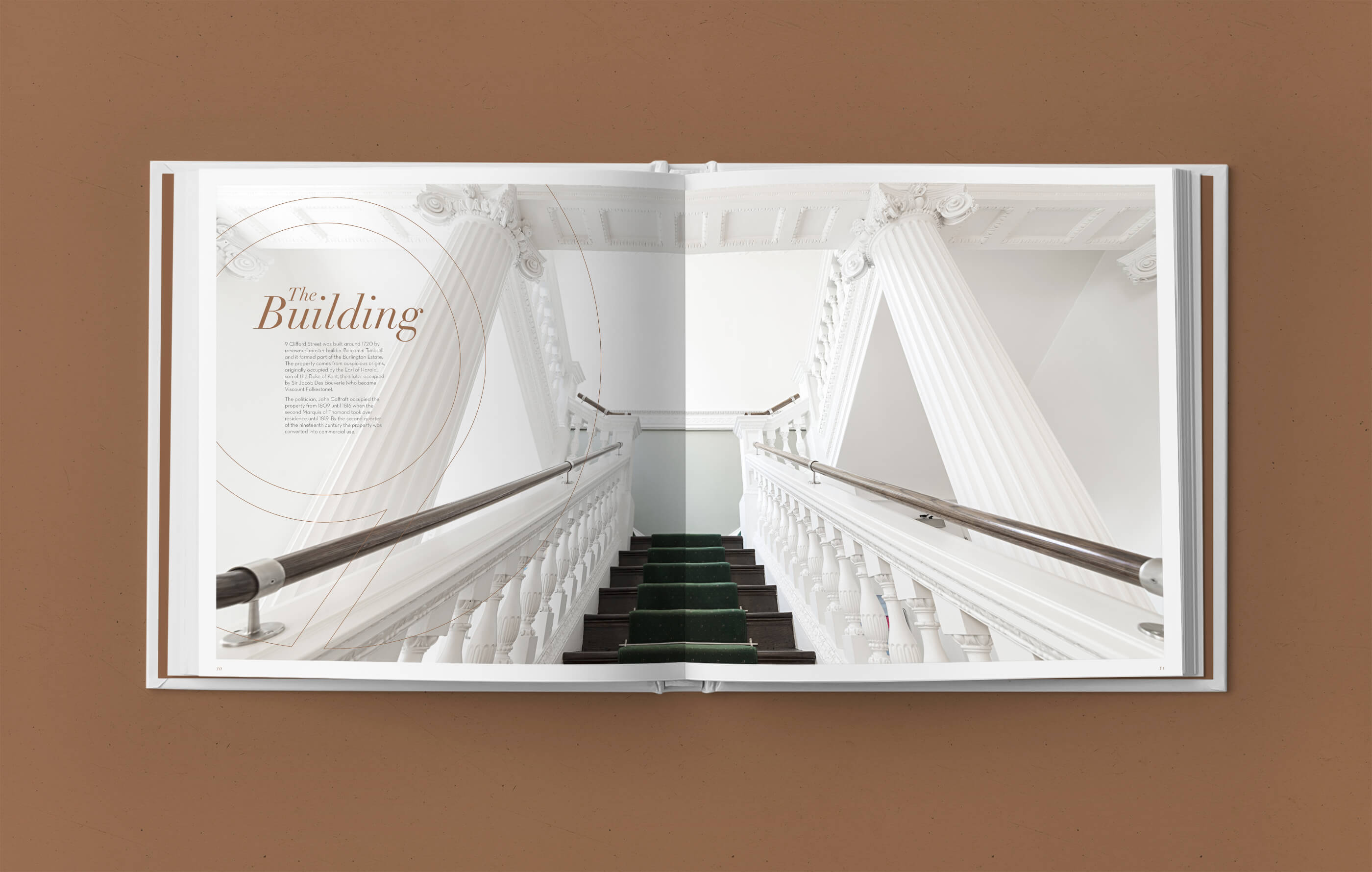Open brochure spread of a sweeping white staircase inside the building, with dark brown steps and royal green stair runner