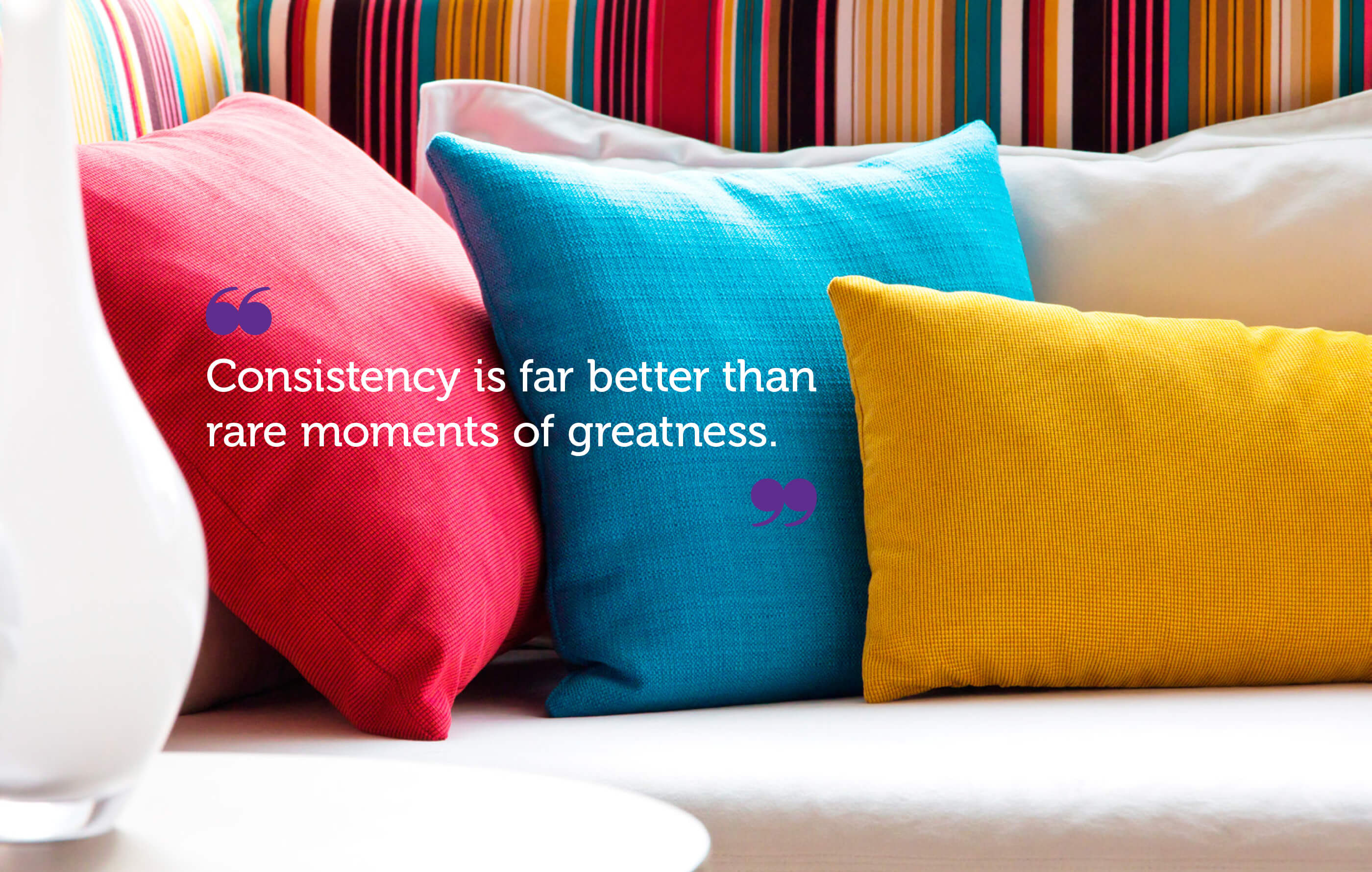 The tagline 'consistency is far better than rare moments of greatness' in white text with purple quote marks on an image of a DFS sofa